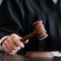 partial view of blurred judge in robe holding gavel in court