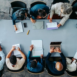 Top view of diverse business group in office meeting, collaborating and discussing around a large table.