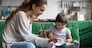 Smiling baby sitter and preschool kid girl drawing with colored pencils sitting on sofa together, single mother and child daughter playing having fun, creative family activities at home concept