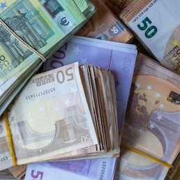 Bundles of European banknotes tied with rubber bands.