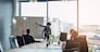Meeting, presentation and whiteboard with a business woman in the boardroom for planning or strategy. Collaboration, flare or report in an office with people around a table during a training workshop.