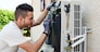 handsome young man electrician installing air conditioning in a client house