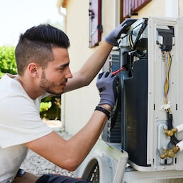 handsome young man electrician installing air conditioning in a client house