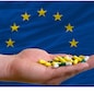 man holding capsules in front of complete wavy national flag of europe symbolizing health, medicine, cure, vitamines and healthy life