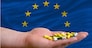 man holding capsules in front of complete wavy national flag of europe symbolizing health, medicine, cure, vitamines and healthy life