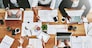 Overhead of colleagues having a marketing meeting in modern office. Above a busy workplace, coworkers brainstorm and develop strategies for a startup business, unity, planning and innovation at work.