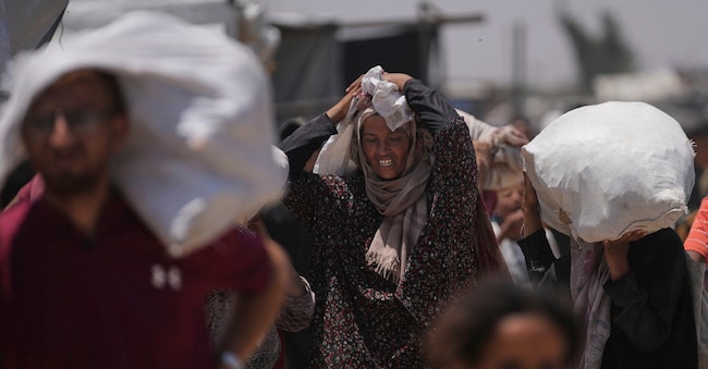 Uomini e donne palestinesi trasportano i sacchi contenenti cibo e aiuti umanitari (Apn)
