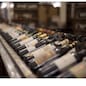 Row of wine bottles with dry red and white wine on wooden. Low depth of field. Winemaking and wine shop concept