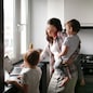 Busy cute woman mom with two children works on a laptop in the kitchen and talks on the phone, mom turns on the kids cartoon. Family concept and freelance work, authentic lifestyle and toning
