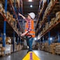 A caucasian female worker pulling a pallet truck in a large distribution center. Woman searching the location of parcel on the shelf for loading the boxes.