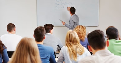 Dozent steht an der Tafel im BWL-Seminar an der Uni