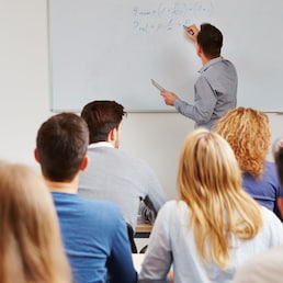 Dozent steht an der Tafel im BWL-Seminar an der Uni