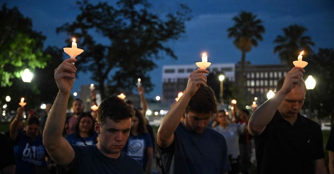 Persone reggono delle candele mentre partecipano a una veglia per le vittime delle inondazioni nel fine settimana del 4 luglio, al Travis Park di San Antonio, Texas