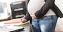Pregnant woman standing and taking notes at office