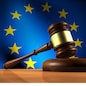 European Union law, legislation and parliament concept with a 3d rendering of a gavel on a wooden desktop and the EU flag on background.