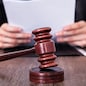Close-up Of Male Judge In Front Of Mallet Holding Documents