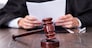 Close-up Of Male Judge In Front Of Mallet Holding Documents