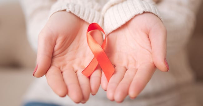 Stop AIDS. Close up of a small red AIDS ribbon being in the womans hands