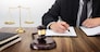lawyer hand writes the document in court (justice, law) with sounding block and golden Weight.