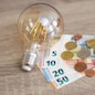 rise of electricity prices concept - light bulb with Euro banknotes and coins