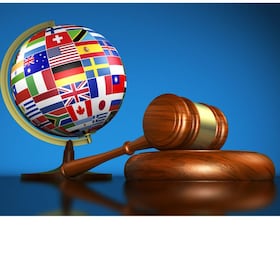 International law systems, justice, human rights and global business education concept with world flags on a school globe and a gavel on a desk on blue background.