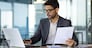 Serious concentrated hispanic businessman financier on paperwork inside office, man in business suit at workplace reviewing and reading papers, contracts and accounts reports