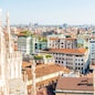 White statue on top of Duomo cathedral and view to city of Milan