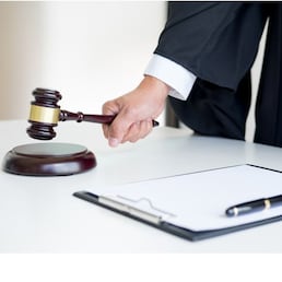 Male Judge lawyer In A Courtroom Striking The Gavel on sounding block.