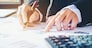 Businessman's hands with calculator at the office and Financial data analyzing counting on wood desk