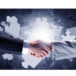 Close up of business handshake with puzzle elements at background