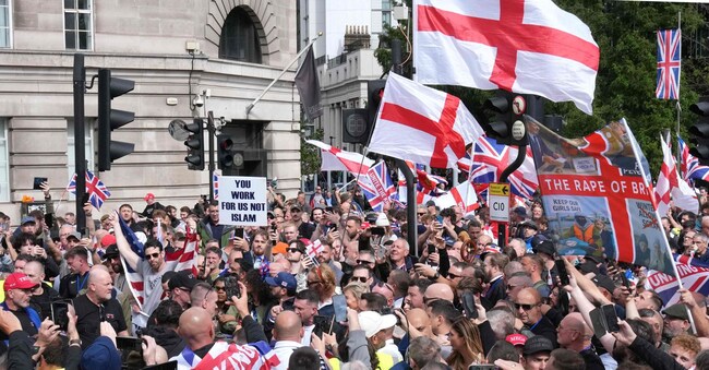  L’attivista britannico Tommy Robinson (al centro), il cui vero nome è Stephen Yaxley-Lennon, si rivolge ai sostenitori mentre sfilano con le bandiere dell’Unione e della croce di San Giorgio nel centro di Londra durante una marcia per la “libertà di parola”, il 13 settembre 2025.(Photo by CARLOS JASSO / AFP)