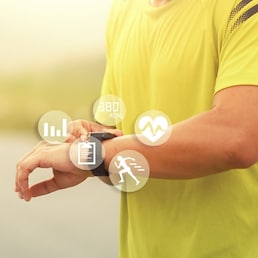 Man runner looks at a modern smart clock and counts up spent calories after training outdoors at sunset. Concept of The technology to check health while exercising.