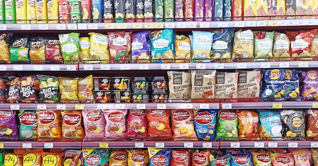 Colorful snack aisle displaying assorted chips and snacks in grocery store.