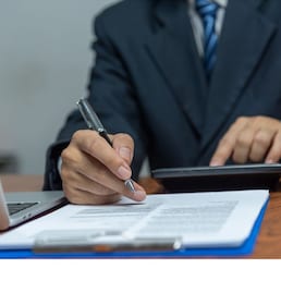 Hand holding pen writing paperwork business document financial investment or signature contract job and insurance on desk.