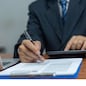Hand holding pen writing paperwork business document financial investment or signature contract job and insurance on desk.