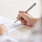 Crop shot of person with pen signing contract at desk in daylight
