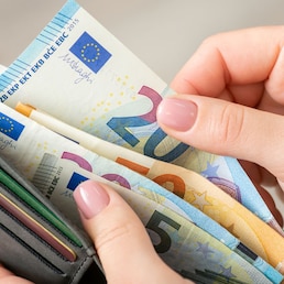 Close up of female hands holding grey wallet with 20 and 50 euro banknotes. Purchases, business, finances concept