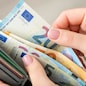 Close up of female hands holding grey wallet with 20 and 50 euro banknotes. Purchases, business, finances concept