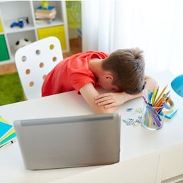 education, cyberbullying and people concept - tired or sad student boy with laptop computer lying on desk at home suffering from bullying
