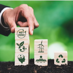 Businessman putting Net Zero symbol cube on stack top for corporate environmental protection and sustainability. Modern house model power by clean wind energy with net zero CO2 emission concept. Alter