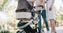 cropped image of mother and father walking with baby carriage in park