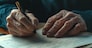 Close-up of an old man's hand studying and signing his last will and testament. Last will and testament concept