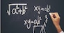 The hand that writes the formula with white chalk on the blackboard
