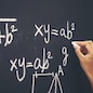 The hand that writes the formula with white chalk on the blackboard