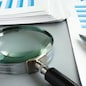 TRN4TB Magnifying glass and business report for auditing.