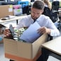 Sad dismissed worker are taking his office supplies with him from office.