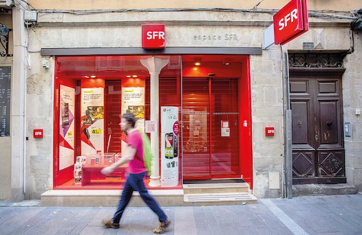 A pedestrian walks past an SFR mobile phone store, operated by SFR SA, a unit of Vivendi SA, in Rodez, France, on Sunday, April 6, 2014. Vivendi SA agreed to sell its French phone unit SFR to Altice SA in a deal valued at more than 17 billion euros ($23 billion), rejecting a sweetened government-backed offer from Bouygues SA. Photographer: Balint Porneczi/Bloomberg via Getty Images Bloomberg via Getty Images