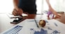 Moving Image of Business creative designer working wooden texture globe with smart phone on business document in office desk as internet concept