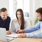 Real estate agent, mortgage broker, bank finance adviser, money loan manager gives pen to young couple clients buyers to sign paper contract after they negotiate his offer at desk with laptop computer