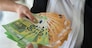 hands of a young beautiful girl hand over a large sum of new euro bills. Business concept